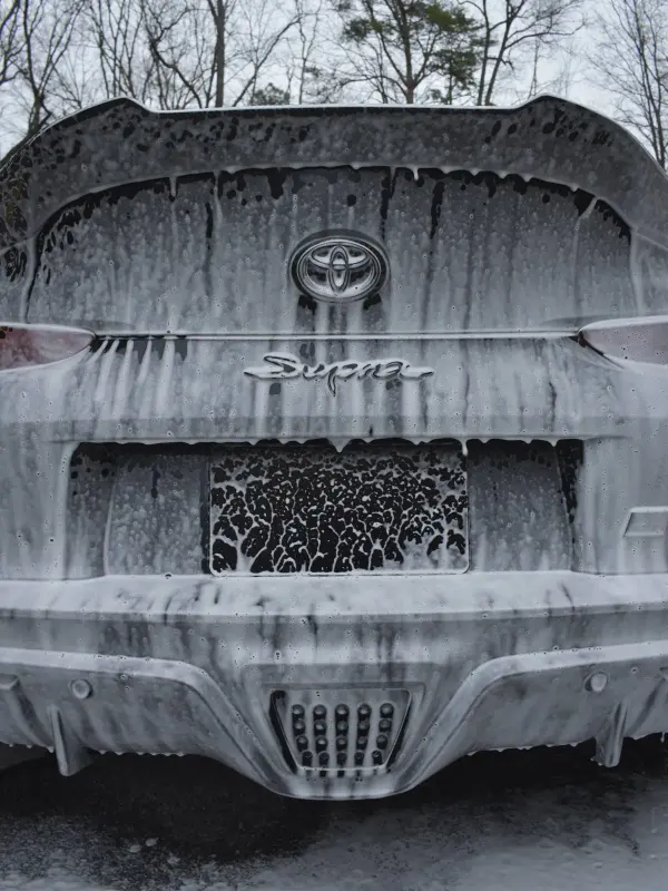 Black Toyota Supra under a thick coat of snow foam