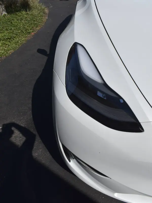 Headlight and paintwork on a white Tesla after a detail